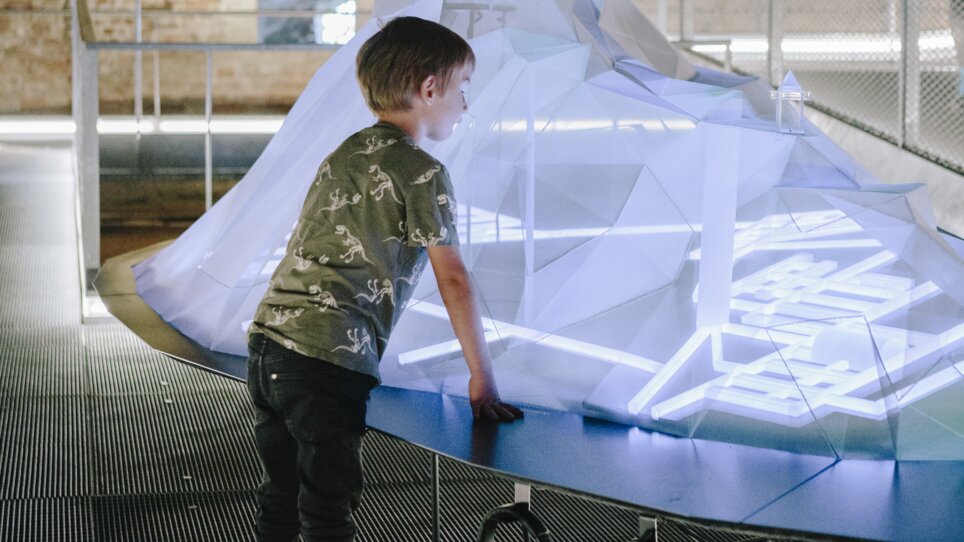 A boy looks at an interactive, glowing installation in a modern space. | © Sebastian Reiser