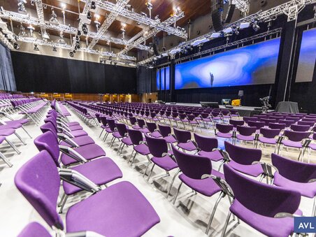 A modern high-ceilinged room with purple chairs arranged in a classroom style. | © Peter Riedler - photoworkers