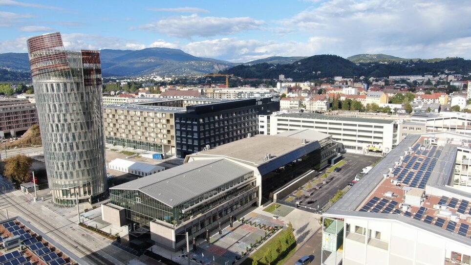 Luftaufnahme eines Geschäftszentrums in Graz, Österreich, mit Blick auf die Berge im Hintergrund. | © Helmut List Halle