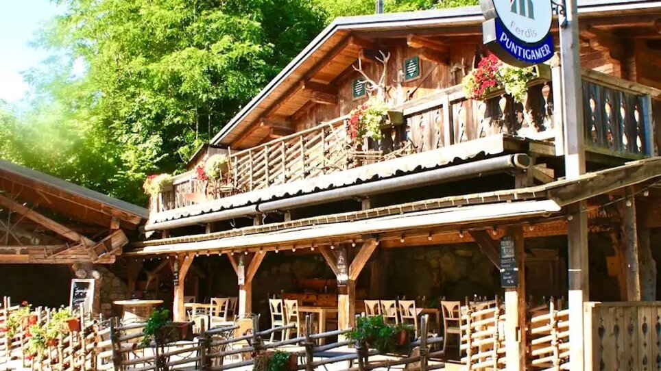 Außenansicht der Almhütte Graz mit Sitzgelegenheiten und Pflanzen. | © I AM Hotels