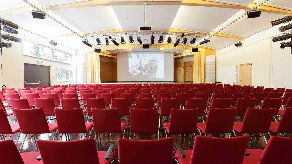Conference hall with rows of red chairs, equipped with technology. | © Markus Kaiser, Graz
