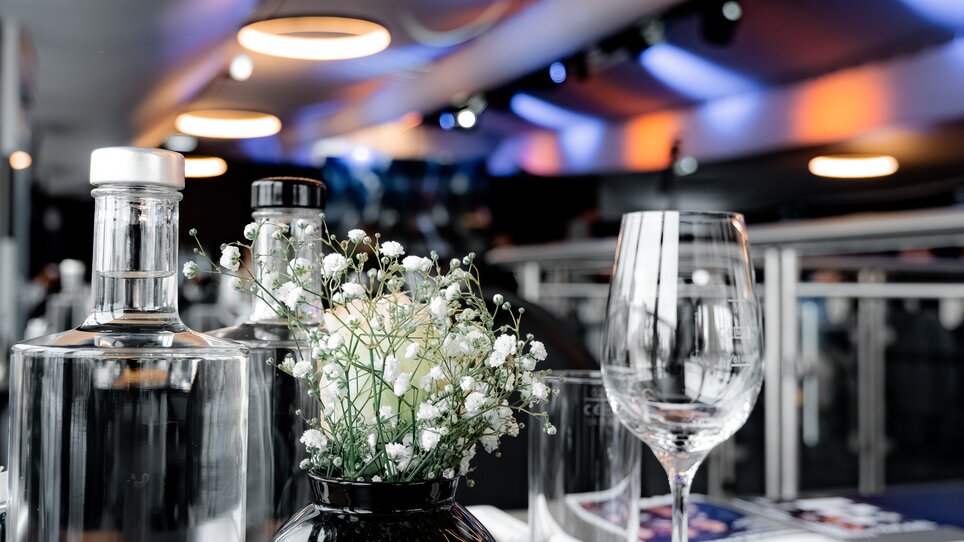 Table with water bottles and flower arrangement at LONGIN GRAWE CLUB 1909. | © Sebastian Atzler