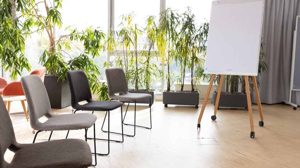 Moderner Meetingraum im Level 4 mit hellen Pflanzen, Stühlen und Flipchart. Ideal für Tagungen und Business-Events. | © Level 4