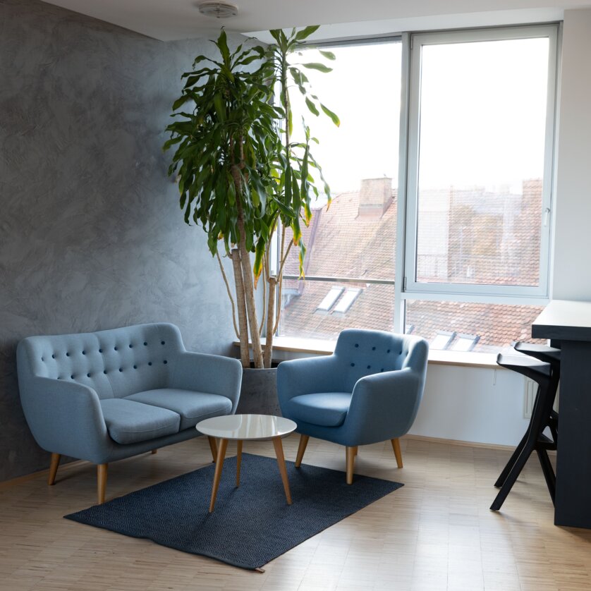 Gemütliche Lounge im Level 4 mit blauen Sofas, einem Tisch und Pflanzen. Helle, moderne Architektur bietet eine einladende Atmosphäre. | © Level 4