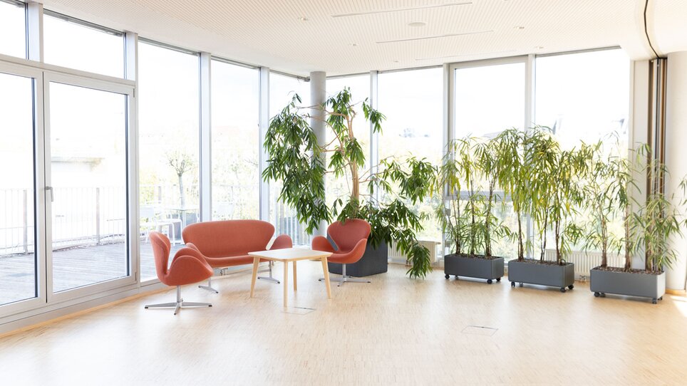 Helle Meetinglocation im Level 4 mit großen Fenstern, orangefarbenen Möbeln und Pflanzen, ideal für Tagungen und Events. Die Atmosphäre ist modern und freundlich. | © Level 4