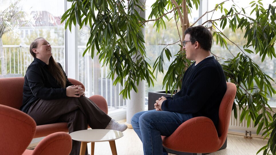 Zwei Personen unterhalten sich entspannt im Level 4. Die moderne, helle Umgebung mit großen Fenstern und Plants führt zu einer angenehmen Atmosphäre für Meetings. | © Level 4