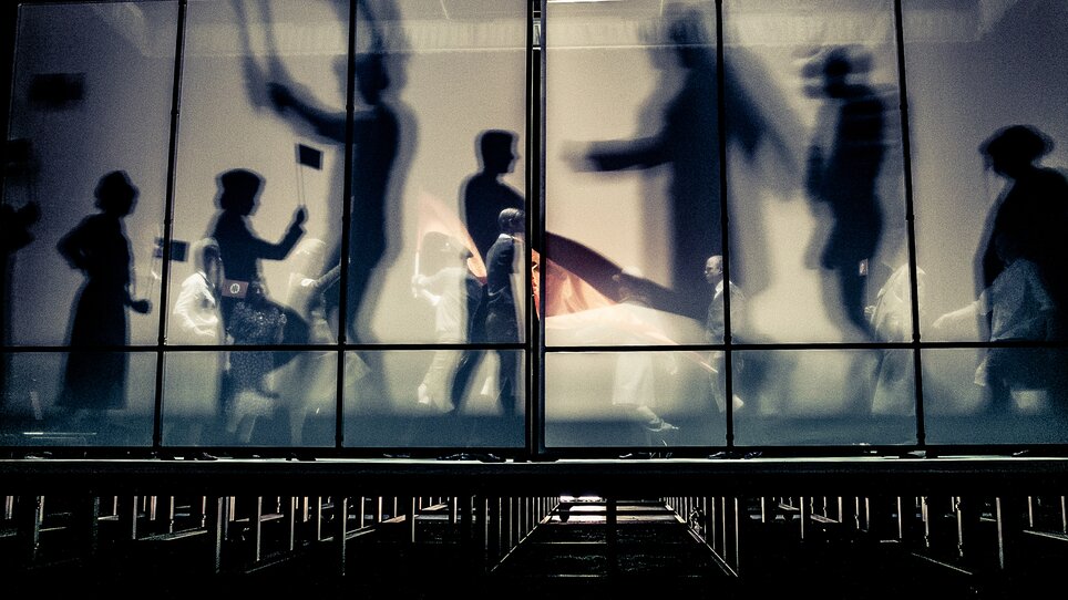 Menschen bewegen sich im Next Liberty, moderne Architektur mit großflächigen Fenstern und einem offenen Raumgefühl. Die Lichtverhältnisse schaffen eine dynamische Atmosphäre für Konferenzen und Networking. | © Lupi Spuma