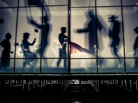 Menschen bewegen sich im Next Liberty, moderne Architektur mit großflächigen Fenstern und einem offenen Raumgefühl. Die Lichtverhältnisse schaffen eine dynamische Atmosphäre für Konferenzen und Networking. | © Lupi Spuma