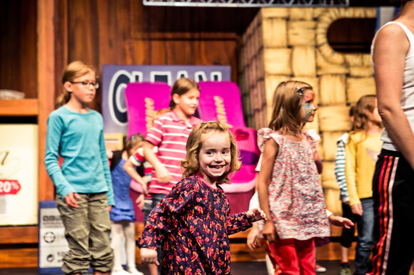 A happy children's ensemble rehearses on stage at Next Liberty. The atmosphere is lively and inviting, perfect for creative events. | © Lupi Spuma