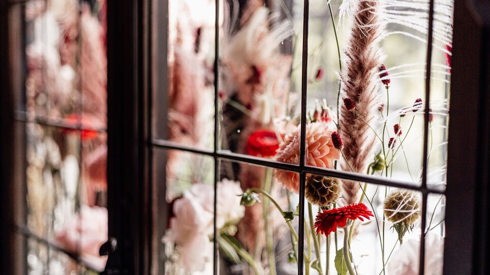 Detailaufnahme von bunten Blumen in einem Fenster im Palais St. Georg. | © Palais St. Georg