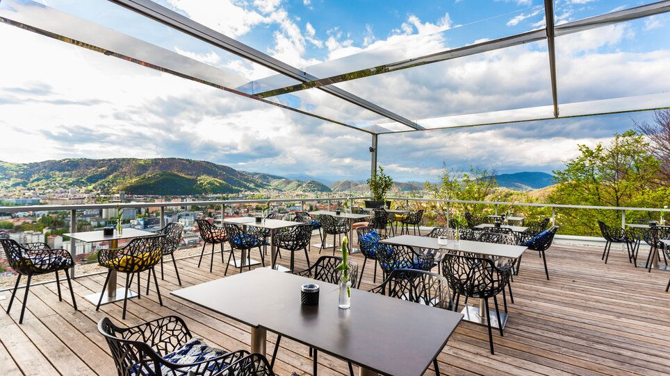 Im Restaurant SCHLOSSBERG bietet eine moderne Terrasse mit Blick auf Graz einen eleganten Rahmen für Tagungen. Die Einrichtung umfasst stilvolle Stühle und Tische, in einem lichtdurchfluteten, offenen Ambiente, ideal für Business-Events. | © Restaurant SCHLOSSBERG - Werner Krug