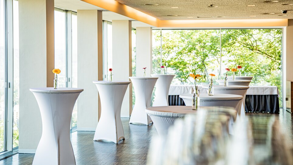 Räumlichkeit im Restaurant SCHLOSSBERG mit eleganten Stehtischen und großen Fenstern, ideal für Business-Events. | © Restaurant SCHLOSSBERG - Werner Krug