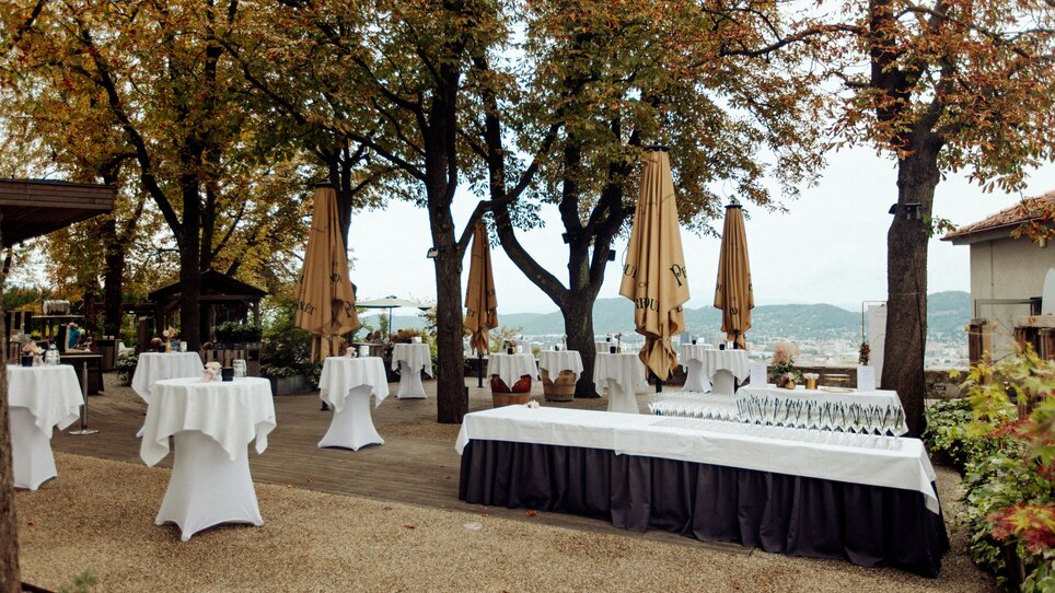 Das Restaurant SCHLOSSBERG bietet eine elegante Terrasse mit runden Tischen, Sonnenschirmen und einer stilvollen Anordnung für Veranstaltungen. | © Restaurant SCHLOSSBERG - Kyrillos Mikhail