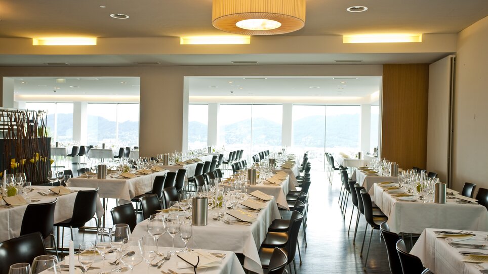 Das Schlossberg Restaurant bietet eine helle, moderne Atmosphäre mit großzügigen Fenstern und stilvollen Tischen. Der Raum ist flexibel gestaltbar für Tagungen und Konferenzen. | © Schlossberg Restaurant