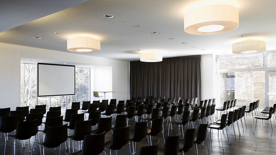 Heller Tagungsraum im Schlossberg Restaurant mit flexibler Bestuhlung für Konferenzen. Der Raum bietet technisches Equipment und große Fenster für viel Tageslicht. | © Schlossberg Restaurant - Paul Ott