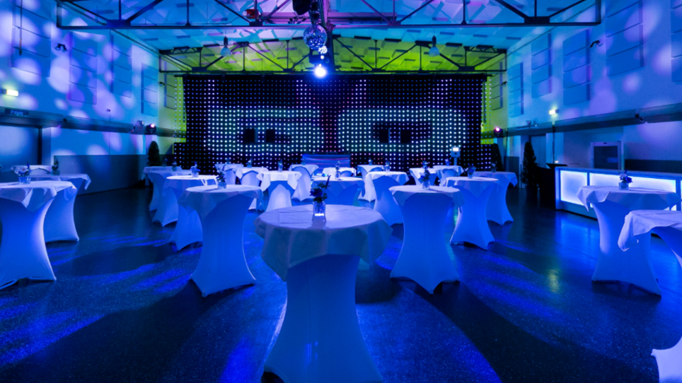 Moderne Eventlocation in Graz mit Tischen und blauer Beleuchtung. | © Oliver Wolf