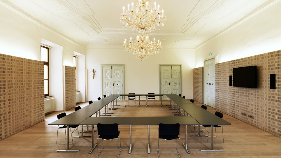 Ein moderner Besprechungsraum im Stift Rein mit großem Tisch, eleganter Beleuchtung und flexibler Möblierung für Tagungen.