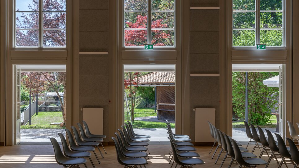 Inside a modern venue featuring chairs and a view of greenery. | © N. Noriller