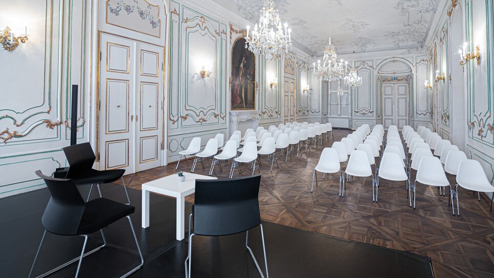 A stylish room for business meetings with white chairs. Paintings adorn the walls. | © Ijob - Brandstätter