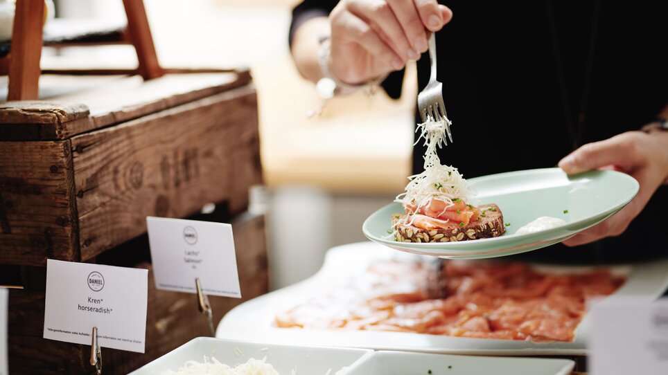 Eine Person serviert eine Portion mit Lachs und Garnitur im Hotel Daniel Graz. | © Florian Weitzer Hotels & Restaurants