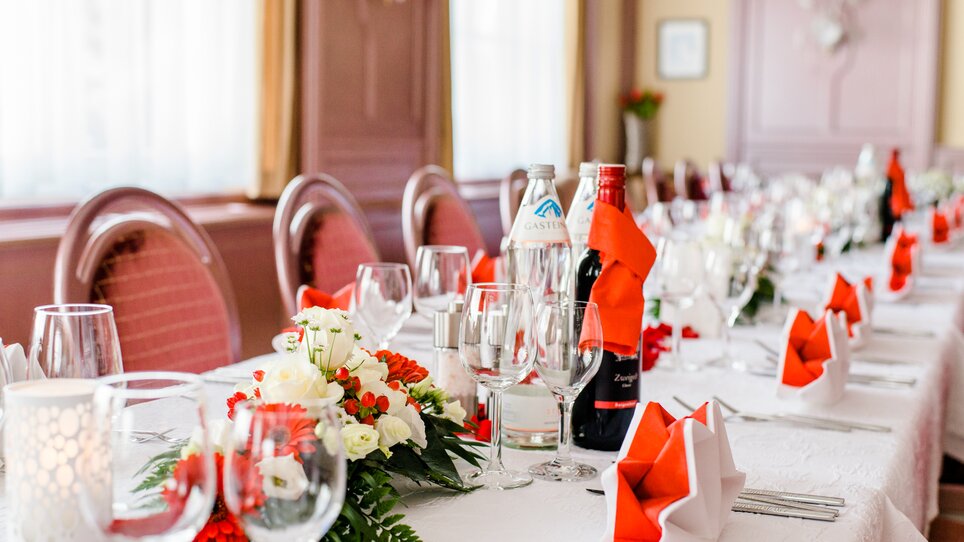 An elegant table with red napkins, flowers, and drinks at Hotel-Gasthof Pendl. | © Mias Photoart