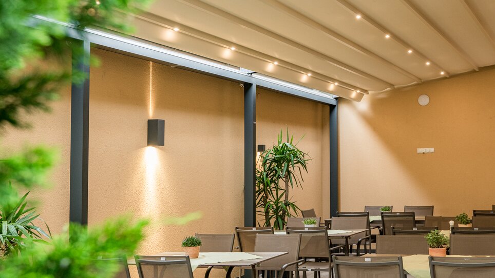 A stylish outdoor restaurant with tables, plants, and gentle lighting at Hotel-Gasthof Pendl. | © Mias Photoart