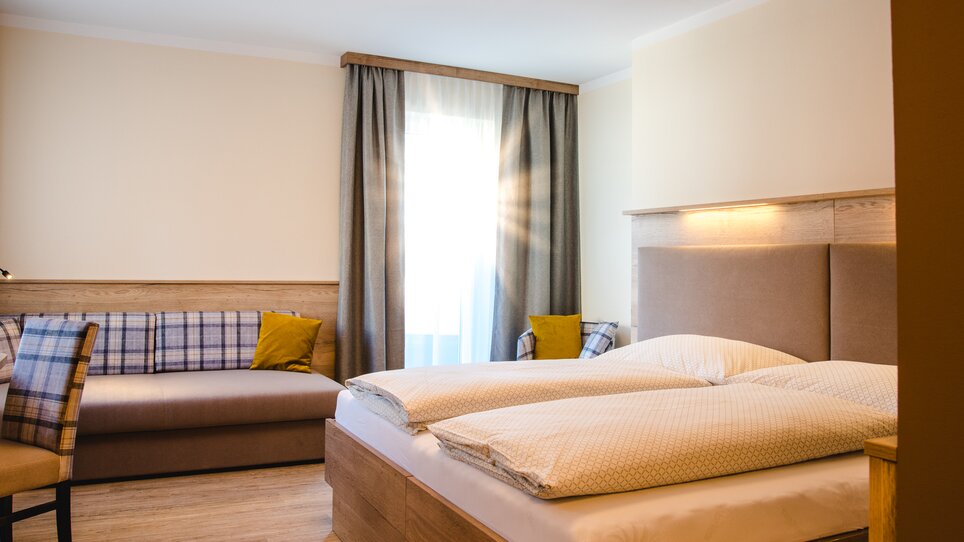 Modern room featuring a double bed and seating area in Hotel-Gasthof Pendl. | © Mias Photoart