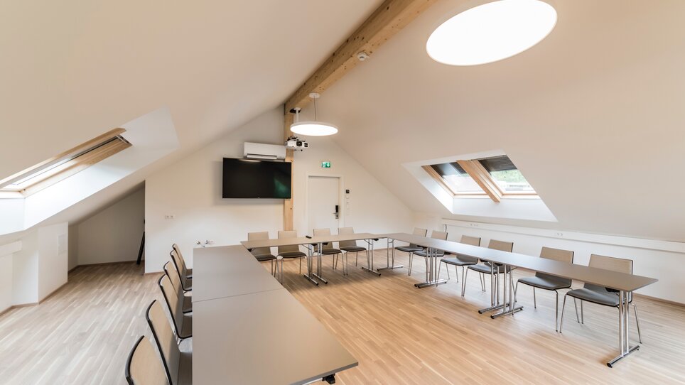 Heller Besprechungsraum mit Tischen und Stühlen für Konferenzen in der Genusspension Herti. | © Grossauer