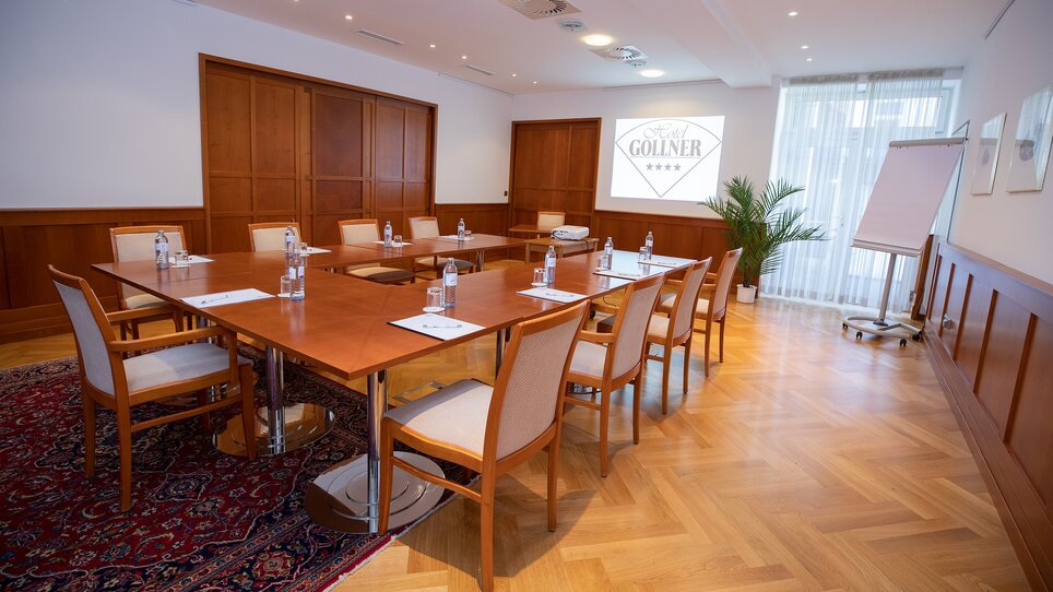Conference room with table, chairs, and presentation setup at Hotel Gollner. | © Hotel Gollner