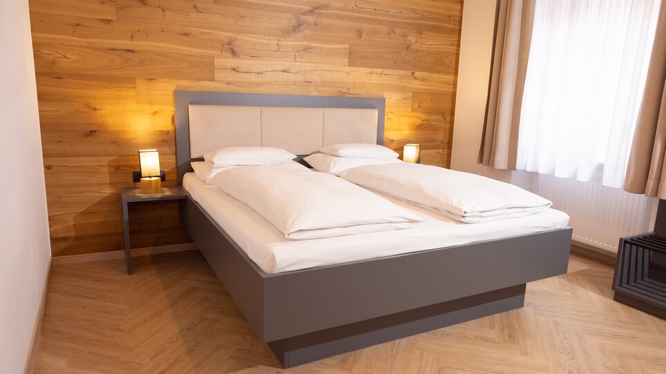 Bright bedroom featuring a double bed and elegant lighting. | © Hotel Gollner