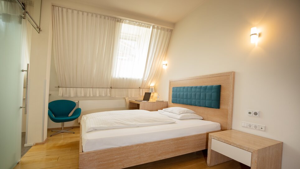 A bright room featuring a bed, desk, and chair at Hotel Gollner. | © Hotel Gollner