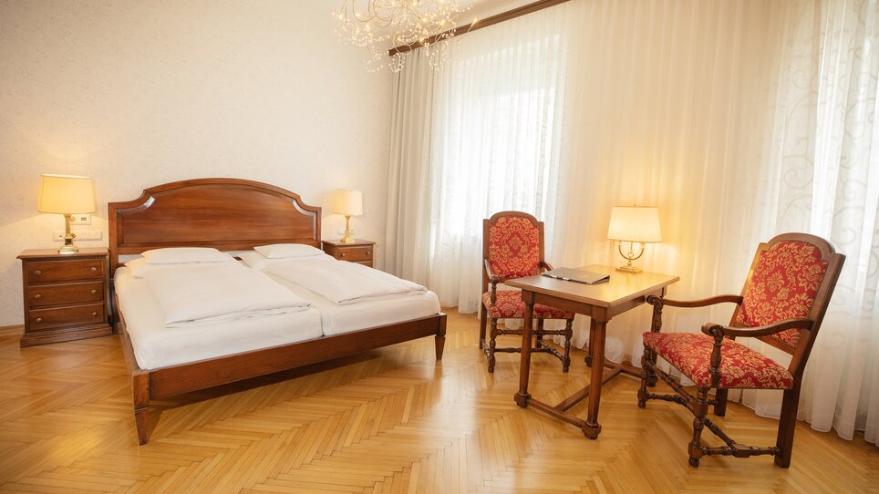 Bright room featuring wooden beds and elegant furniture at Hotel Gollner. | © Hotel Gollner