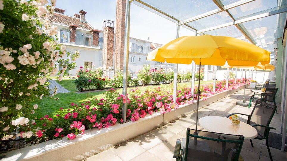 Bright garden area with colorful flowers and sun umbrellas. Ideal for relaxing meetings at Hotel Gollner. | © Hotel Gollner