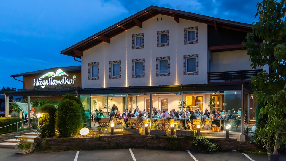 Das Restaurant Hügellandhof bei Dämmerung mit Gästen im Freien. | © Hügellandhof