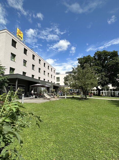 Außenansicht des JUFA Hotels Graz City mit Sitzgelegenheiten im Garten für Tagungen und Geschäftsreisen. | © JUFA Graz City