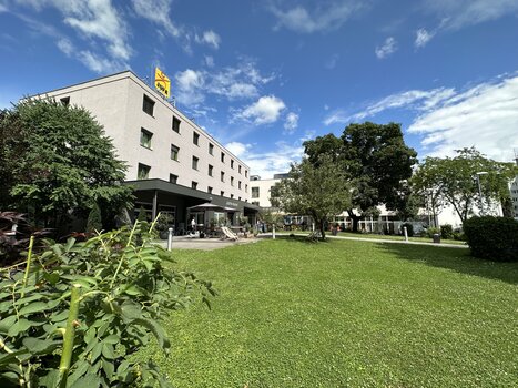 Exterior view of JUFA Hotel Graz City with seating areas in the garden for conferences and business trips. | © JUFA Graz City