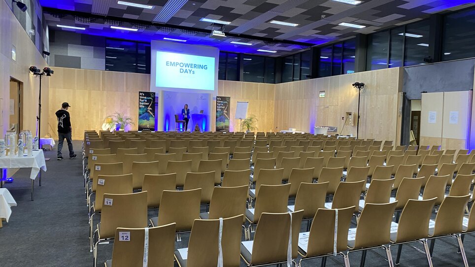 Conference room at JUFA Hotel Maria Lankowitz set for 'Empowering Days' with rows of chairs and presentation screen. | © JUFA Hotels - Monika Heinrich
