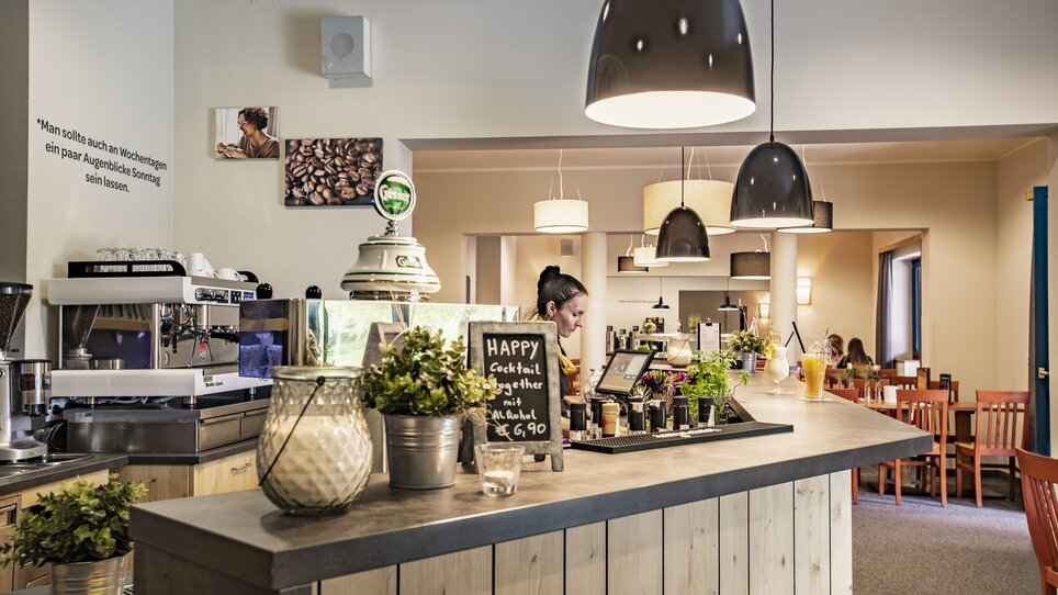 Café area with a counter, barista, and cocktails at the JUFA Hotel Maria Lankowitz. | © LenzJUFA Hotels
