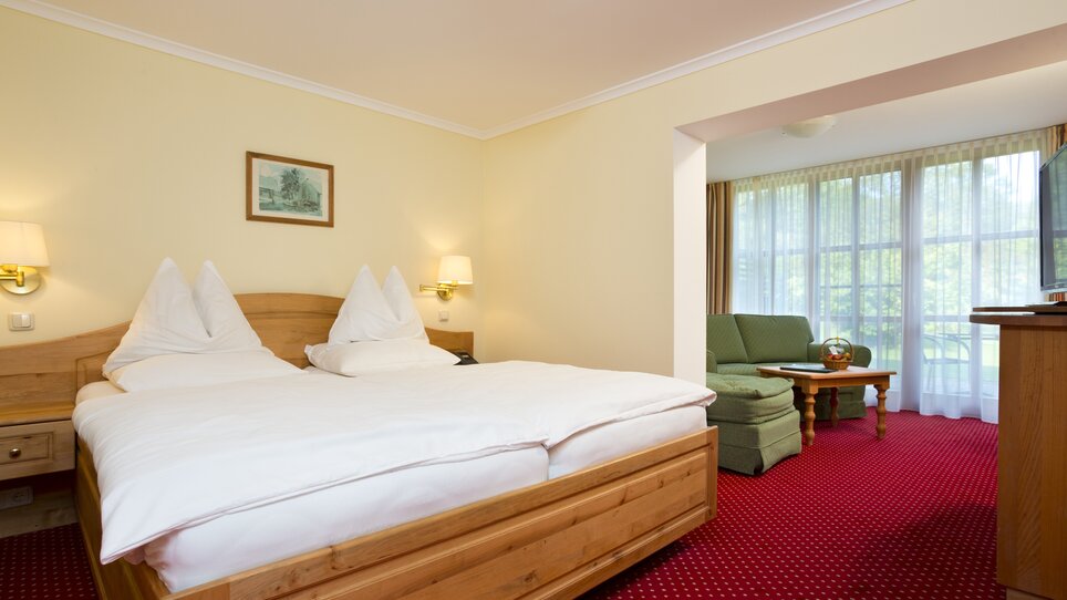 Ein helles Hotelzimmer mit Doppelbett und Wohnzimmer-Ecke im Murhof Hotel & Restaurant. | © Murhof