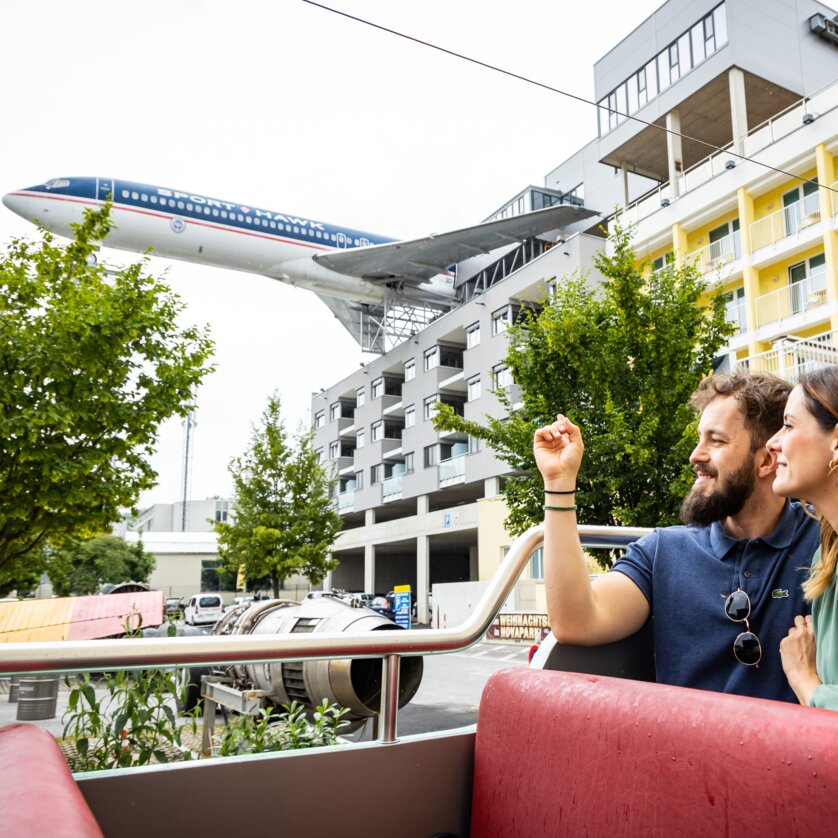 Paar im Novapark Flugzeughotel mit einem Flugzeug im Hintergrund. | © Graz Tourismus - Werner Krug