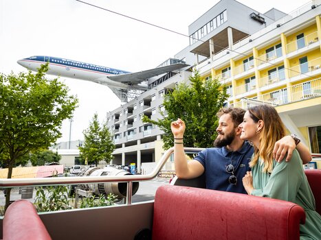 Couple at Novapark aircraft hotel with an airplane in the background. | © Graz Tourismus - Werner Krug