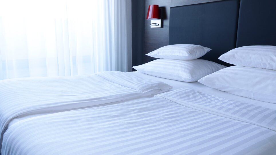 Ein stilvolles Doppelbett in einem modernen Hotelzimmer im PLAZA INN Graz City. | © PLAZA INN Graz City - Kitti Bazsika