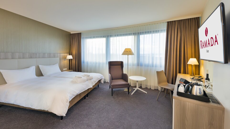 Ein Doppelzimmer im Hotel Ramada Graz mit zwei Betten und Sitzmöglichkeiten. | © Hotel Ramada Graz