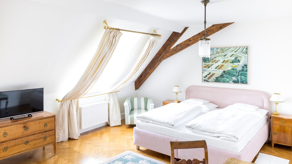 Helles Schlafzimmer mit Doppelbett, TV und Ausblick im Schlossberghotel. | © Schlossberghotel