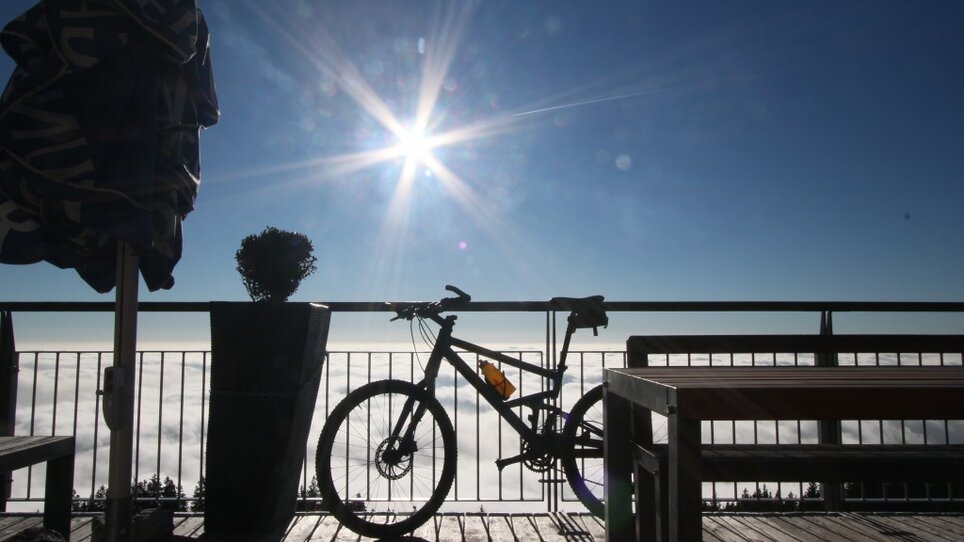 Bicycle and terrace overlooking clouds under sunlight at the Stubenberghaus. | © Stubenberghaus