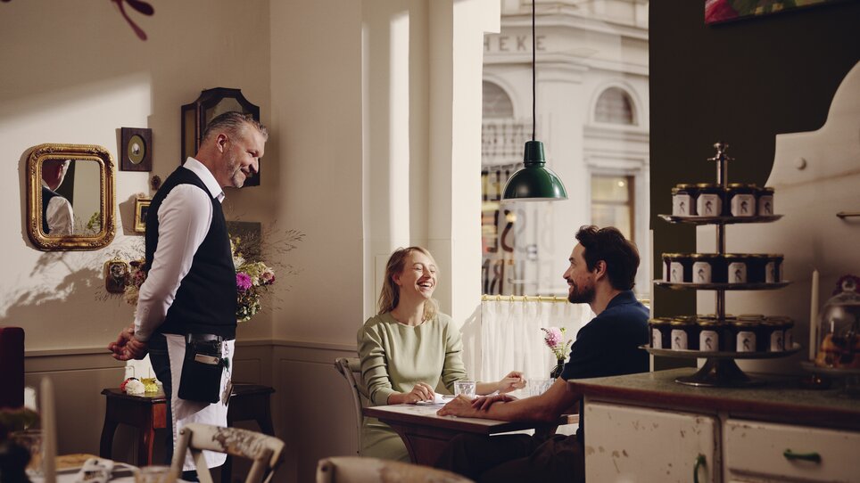 Guests enjoying a meal in the restaurant in Hotel Das Weitzer, waitress serving dishes. | © Florian Weitzer Hotels & Restaurants