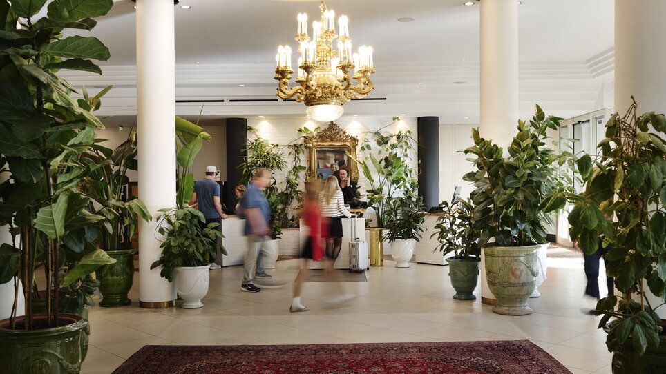 Empfangsbereich im Hotel Weitzer mit Pflanzen und Gästen. | © Florian Weitzer Holding GmbH