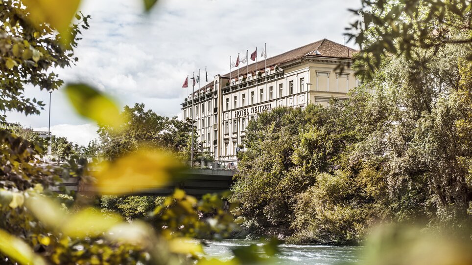 View of Hotel Das Weitzer in Graz, framed by trees and the Mur river. | © Florian Weitzer Hotels & Restaurants