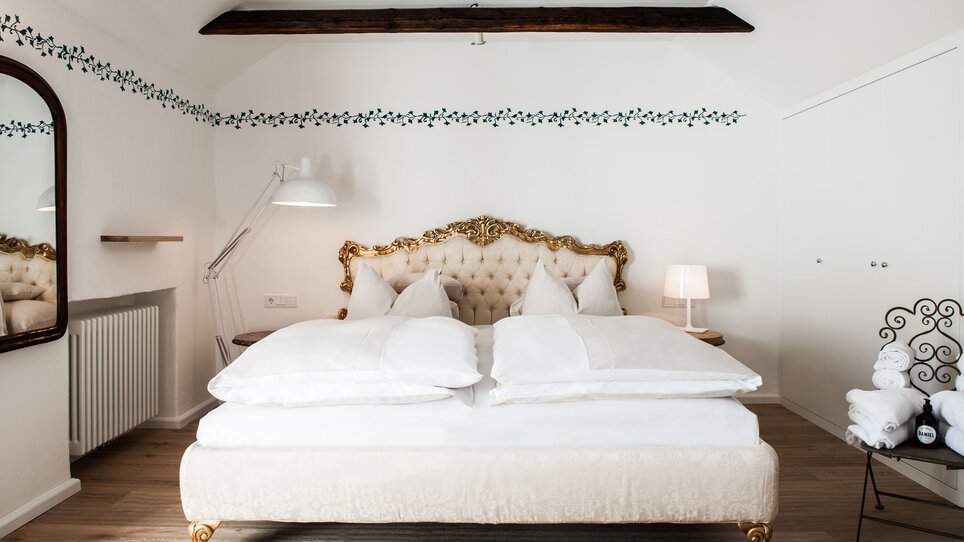 Ein stilvolles Schlafzimmer mit goldenen Elementen im Hotel Weitzer. | © Florian Weitzer Hotels & Restaurants