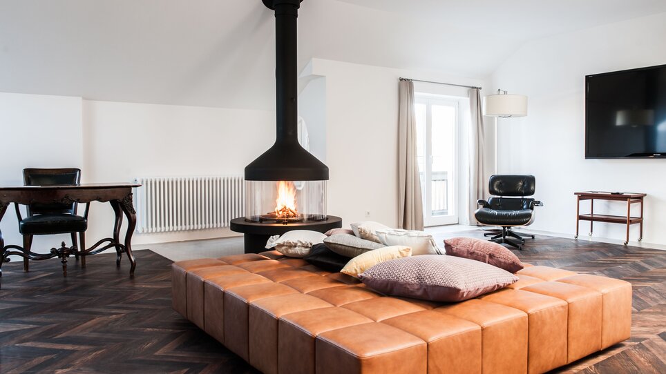 Moderner Wohnbereich mit offener Feuerstelle und Sitzkissen. | © Florian Weitzer Hotels & Restaurants